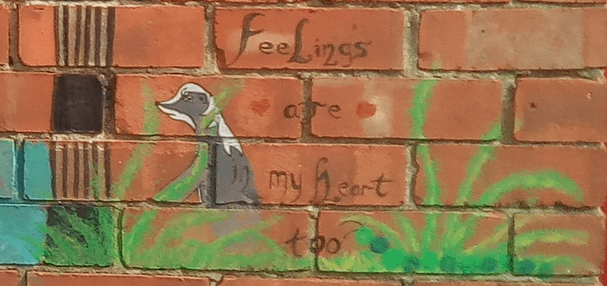 Part of Yvonne Ivey's "My art therapy wall". Here you can see a dog, some grass and the words "Feelings are in my heart too"